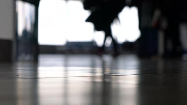 4K ground level soft focus video clip of anonymous people walking through an airport terminal with suitcases, bags and baggage