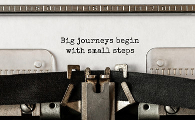Text Big journeys begin with small steps typed on retro typewriter