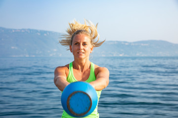 junge sexy sportlerin frau trainiert am see mit Kettlebell Cross Fit training urban sport Uebungen