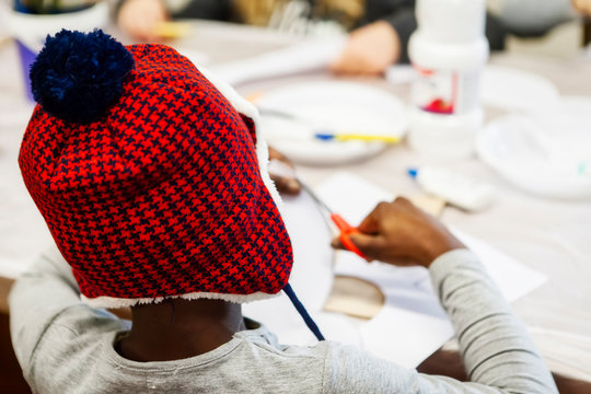 Black kid cutting paper at creative laboratory