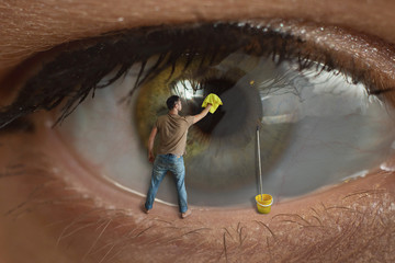 Male worker cleaning the surface of the pupil of the eye with a rag. Concept of healthy eyesight, conjunctivitis and window cleaning.