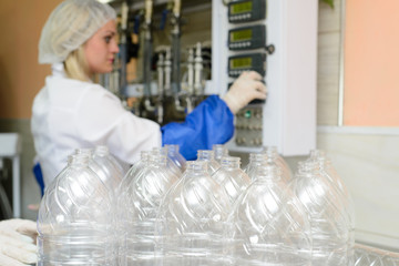 line of production of refined sunflower oil. Girl worker at a factory on a conveyor background with bottles of vegetable oil.