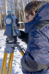 A surveyor enters the survey data for a cadastre at a construction site during the winter period.