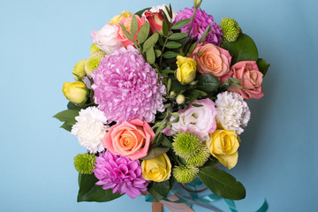 beautiful floral arrangement, pink and yellow rose, pink eustoma, green and pink chrysanthemum, white carnation, pink dahlia on a blue, turquoise background with space for text.