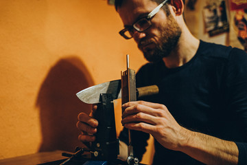 Mann schärft ein japanisches Kücchenmesser an einem modernen Schleifwerkzeug