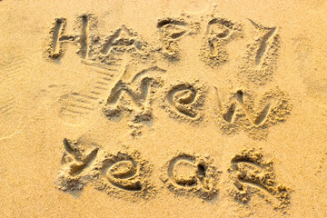 Hand inscription Happy New Year on the sand. 