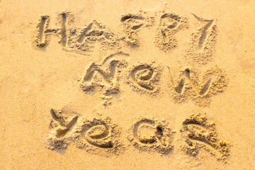Handwriting Happy New Year on the sand. 