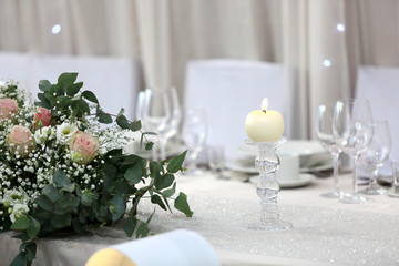 Biała świeca i bukiet kwiatów na białym stole. - obrazy, fototapety, plakaty