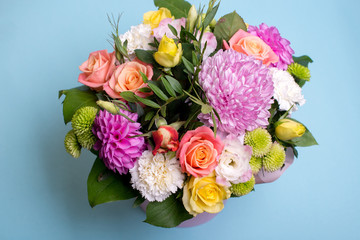 beautiful floral arrangement, pink and yellow rose, pink eustoma, green and pink chrysanthemum, white carnation, pink dahlia on a blue, turquoise background with space for text.
