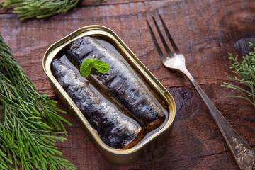 Tin of sardines with Mentha spicata on a rustic table.