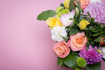 beautiful floral arrangement in the box, pink and yellow rose, pink eustoma, green and pink chrysanthemum, white carnation, pink dahlia on pink background with space for text.