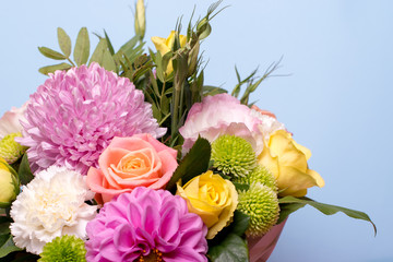 beautiful floral arrangement, pink and yellow rose, pink eustoma, green and pink chrysanthemum, white carnation, pink dahlia on a blue, turquoise background with space for text.