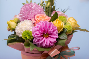 beautiful floral arrangement, pink and yellow rose, pink eustoma, green and pink chrysanthemum, white carnation, pink dahlia on a blue, turquoise background with space for text.