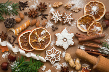 Christmas decoration with spices and cookies in the shape of snowflakes, cinnamon sticks and star anise on dark brown paper background. Top view.