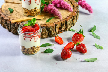 layered dessert with strawberries, biscuit cake and cream cheese on a white wood background. selective focus