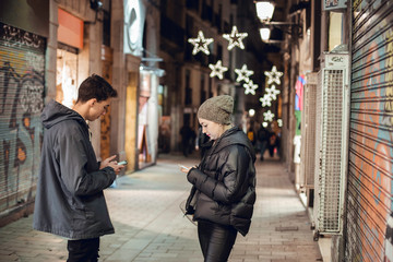 Couple of friends using their mobile phone