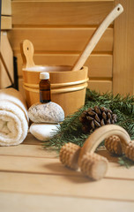Spa, sauna and wellness setting with water bucket, oil essence, cones, Christmas tree branches, white towel on wooden background. winter wellness concept relax and treatment therapy. Selective focus