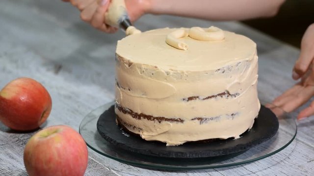 A chef decorates a cake with a cream.