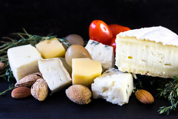 Cheese with grapes, tomato, almond and thyme. Food on black background.