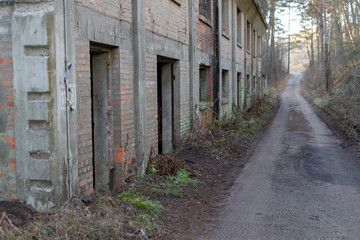 Factory ruins in a wooded area. Abandoned building and forest road.