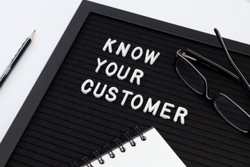 Know Your Customer - business concept, white text message on black board with notebook