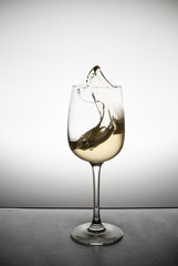 splash of white wine in a glass