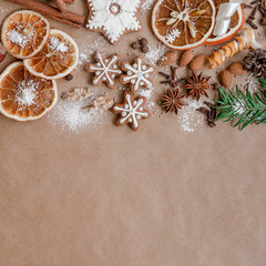 Obraz na płótnie Canvas Christmas decoration with spices and cookies in the shape of snowflakes, cinnamon sticks and star anise on dark brown paper background. Top view.