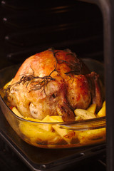 baked chicken with a crispy crust on a baking sheet in a dark oven