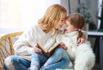 happy family mother reads book to child to daughter by window