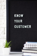 Know Your Customer - business concept, white text message on black board, stack of notebooks