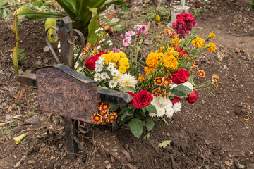 Old rusty grave tomb. Flowers offered for an unknown human