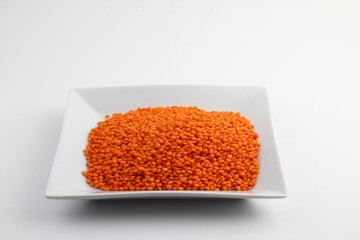 Red lentils in glass bowl isolated on white background. Top view