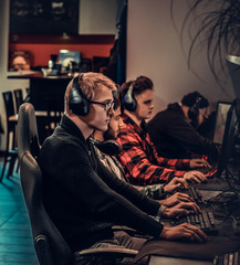 Fototapeta na wymiar Team of teenage gamers plays in a multiplayer video game on pc in a gaming club.