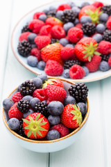 Fresh berry salad on blue dishes. Vintage wooden background.