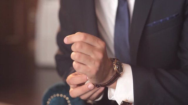 Close-up of a successful man is putting on a wristwatch. Men