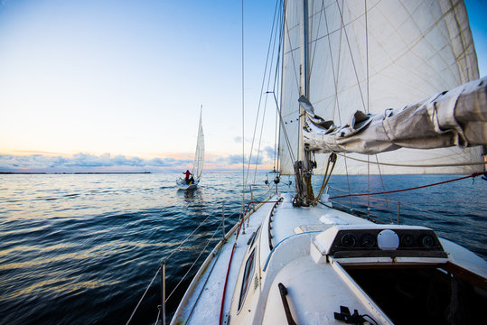 Fototapeta Clear evening sky at sunset. Two yachts sailing. A view from the deck to the bow and sails, close-up. Baltic sea, Latvia