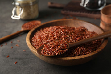 Brown rice in spoon and bowl on table