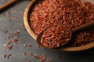 Closeup view of brown rice in spoon and bowl on table