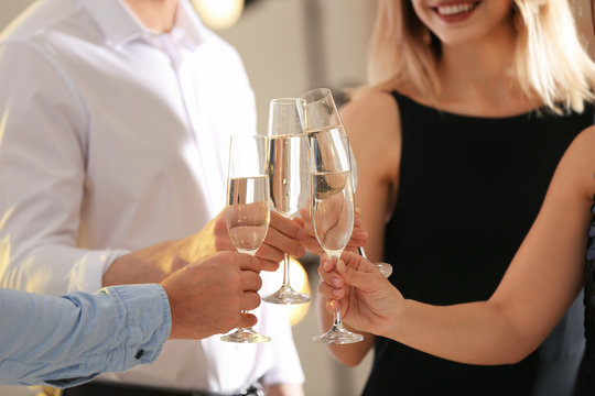 Friends clinking glasses with champagne at party indoors, closeup