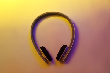 Stylish modern headphones with earmuffs on color background, top view