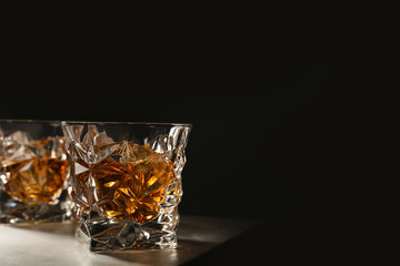 Golden whiskey in glass with ice cubes on table. Space for text