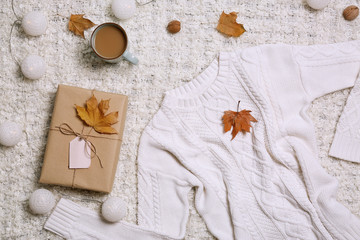 Flat lay composition with warm sweater on light fabric