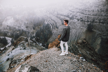 A young guy on the edge in the mountains