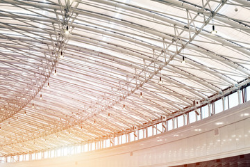 Curved big shoppimg mall roof indoors. Modern metal and glass ceiling contruction
