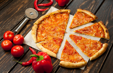 pizza on a wooden table with ingredients, tomato, pepper, sunflower oil