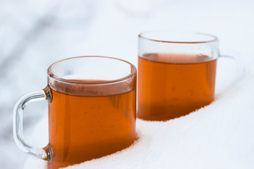 Two cups with hot tea in the snow
