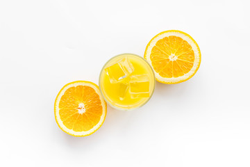 Glass of cold orange juice near halfs of fresh oranges on white background top view pattern copy space