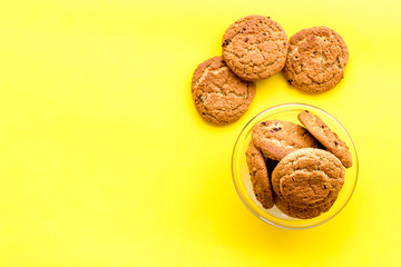 Homemade oatmeal cookies in glass bowl on yellow background top view copy space