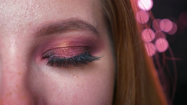 Caucasian blonde girl, close-up green eye in makeup and eyeshadows looking straight at camera on black background and nit blinking, natural sight, cosmetics illustration