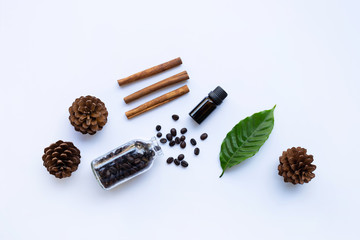 Glass bottle of coffee essential oil  and cinnamon on white